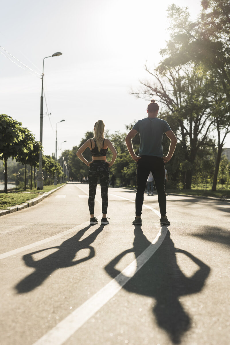 Jovens se preparando para caminhada e corrida em avenida arborizada, buscando melhor resultado na caminhada.