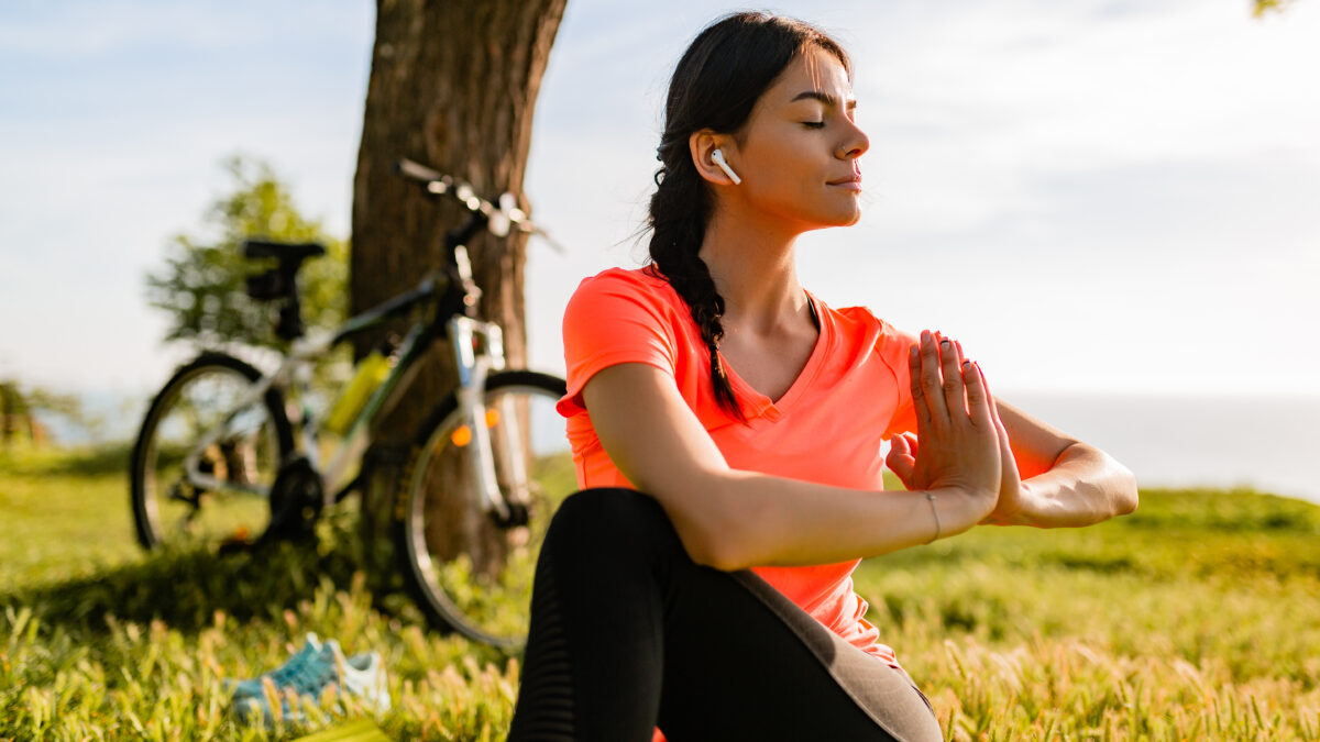Mulher fazendo ioga no parque, unindo saúde mental e exercício.