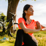 Mulher fazendo ioga no parque, unindo saúde mental e exercício.