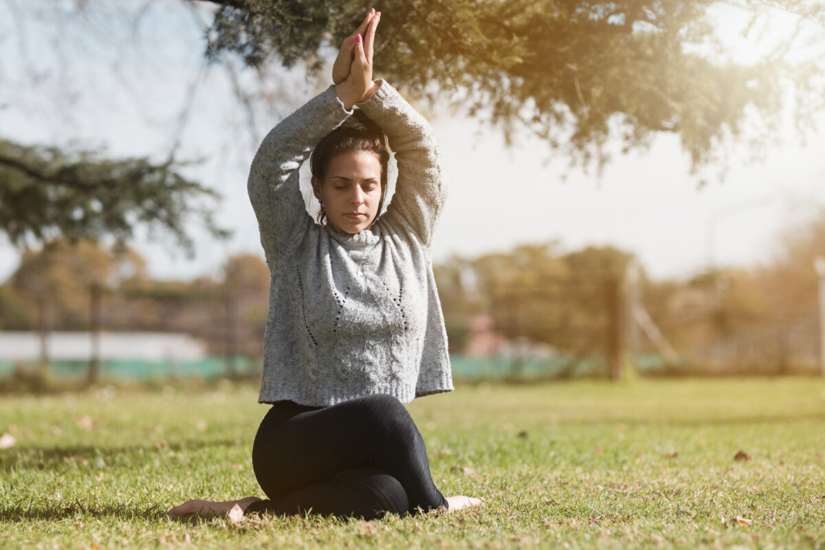 Mulher praticando ioga ao ar livre para melhorar a saúde mental e exercício.