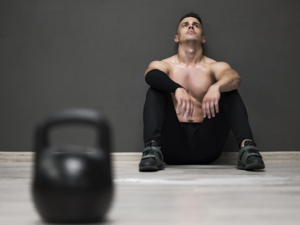 Homem descansando após o treino, pensando em desistir da academia em janeiro.