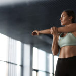 Mulher realizando alongamento antes do treino como parte de uma rotina equilibrada para resultados na academia.